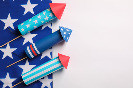 Firework rockets and USA flag on white background, flat lay with space for text. Festive decorの写真素材