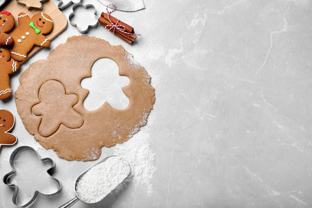 Flat lay composition with homemade gingerbread man cookies on light gray table, space for text