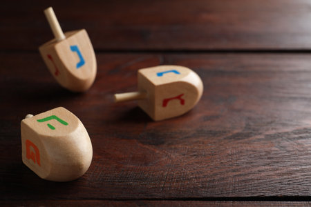 Hanukkah traditional dreidel with letters Pe and He on wooden table. Space for textの写真素材