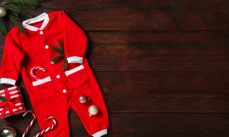 Flat lay composition with cute Christmas baby clothes on wooden background. Space for textの写真素材