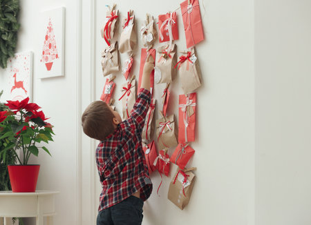 Cute little boy taking gift from Advent calendar at home. christmas traditionの写真素材