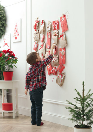 Cute little boy taking gift from Advent calendar at home. christmas traditionの写真素材