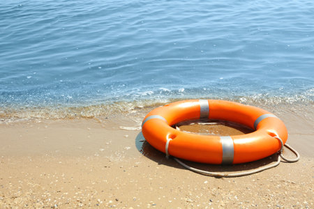 Orange life buoy on sand near the sea. emergency rescue equipmentの写真素材