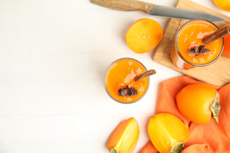 Tasty persimmon smoothie with anise and cinnamon on white wooden table, flat lay. Space for textの写真素材