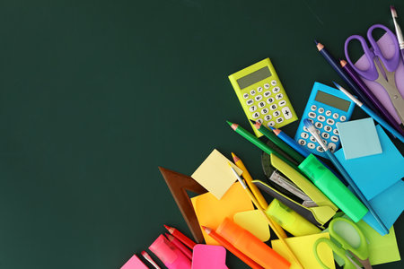 Flat lay composition with different school stationery on green chalkboard, space for text. back to...