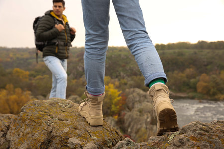 Couple of hikers with backpacks climbing up mountains, closeup