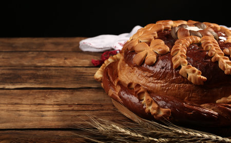 Korovai with wheat spikes on wooden table against black background, space for text. Ukrainian bread and salt welcoming traditionの写真素材