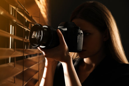 Private detective with camera spying near window indoorsの写真素材