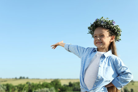 Cute little girl wearing flower wreath outdoors, space for text. child spending time in natureの写真素材