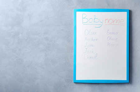 White board with baby names on gray wall. Space for textの写真素材