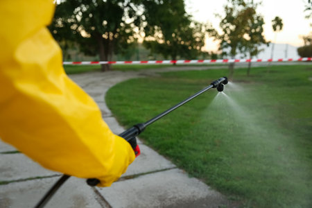 Person in hazmat suit disinfecting street with sprayer, closeup.の写真素材