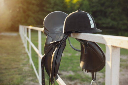 Leather horse saddle and helmet on wooden fence outdoorsの写真素材