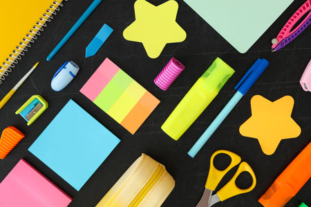 Flat lay composition with different school stationery on blackboard. back to school