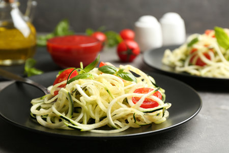 Delicious zucchini pasta with cherry tomatoes and basil on light gray table, closeupの写真素材