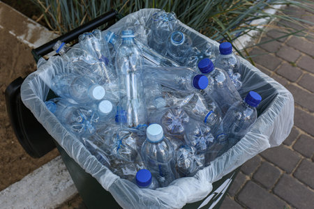 Many used plastic bottles in trash bin outdoors. recycling problem
