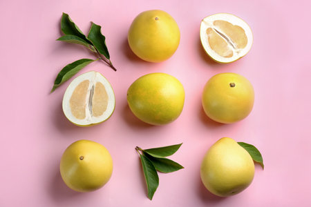 Fresh cut and whole pomelo fruits with leaves on pink background, flat layの写真素材