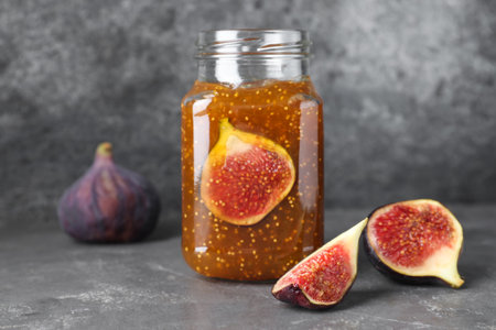 Delicious fig jam and fresh fruits on gray tableの写真素材