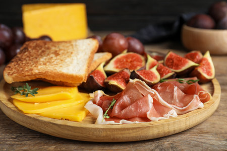 Delicious ripe figs, prosciutto and cheese served on wooden table, closeupの写真素材