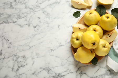 Fresh ripe organic quinces with leaves on white marble table, flat lay. Space for textの写真素材