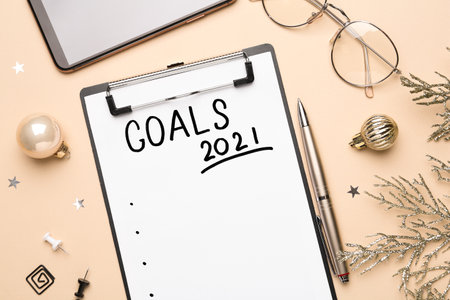 Flat lay composition with clipboard and festive decor on beige background. Goals for New Year 2021の写真素材