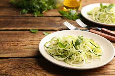 Tasty zucchini pasta with basil served on wooden table. Space for textの写真素材