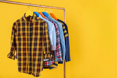Rack with stylish children clothes on yellow backgroundの写真素材