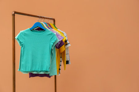 Rack with stylish children clothes on beige background. Space for textの写真素材