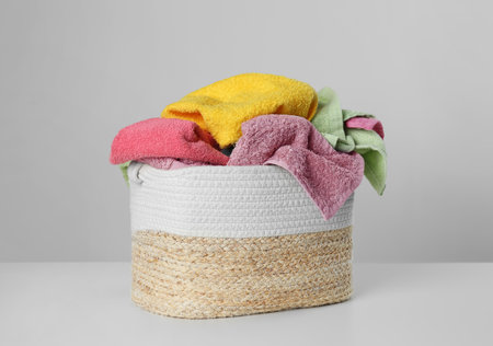 Wicker laundry basket with towels on light backgroundの写真素材