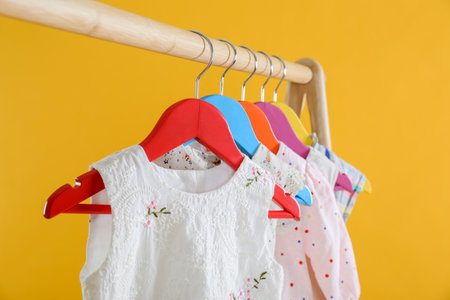 Rack with stylish children clothes on yellow background, closeupの写真素材
