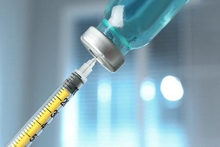 Filling syringe with medication from vial against blurred background, closeup. Vaccination and immunizationの写真素材