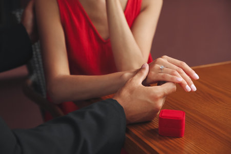Man with engagement ring making proposal to his girlfriend at table, closeup