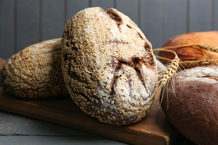 Loaves of delicious fresh bread on gray wooden table, closeup