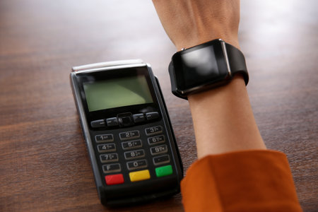 Woman making payment with smart watch at table, closeupの写真素材