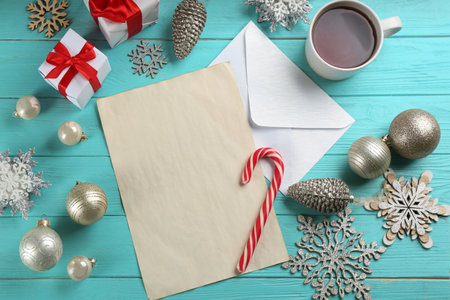 Flat lay composition with blank sheet of paper and Christmas decorations on turquoise wooden table, space for text. Writing letter to Santaの写真素材