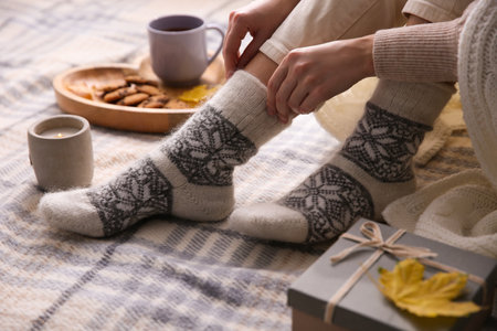 Woman wearing warm socks on checkered plaid, closeup. Cozy season