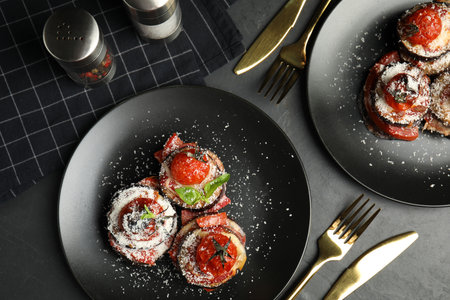 Baked eggplant with tomatoes, cheese and basil served on black table, flat layの写真素材