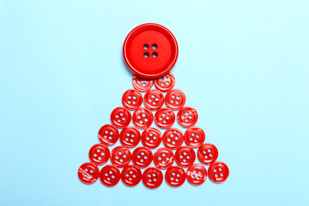 Christmas tree made with red buttons on light blue background, flat layの写真素材