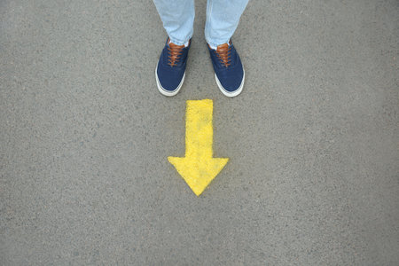 Man standing near arrow on asphalt, top view