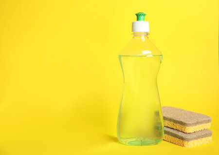 Cleaning product and sponges on yellow background, space for text. Dish washing suppliesの写真素材