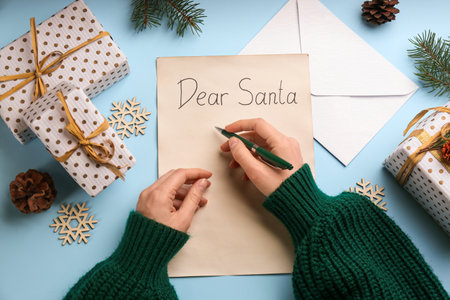 Top view of woman writing letter to Santa at light blue table, closeupの写真素材