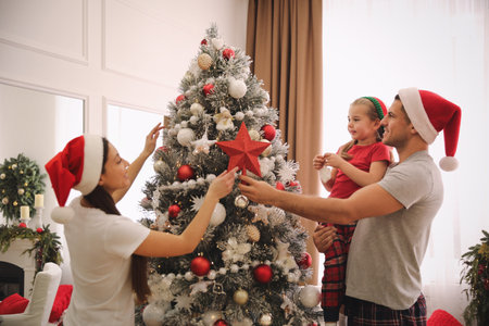 Family decorating Christmas tree with star topper indoorsの写真素材