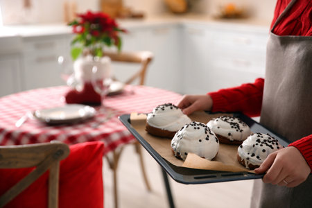 Woman with sweet buns for Christmas dinner in kitchen, closeup