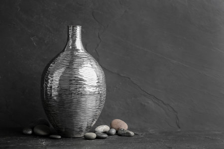 Stylish silver ceramic vase and rocks on black table, space for textの写真素材
