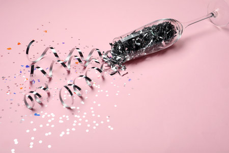 Glass and shiny confetti on pink backgroundの写真素材