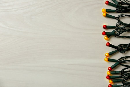 Beautiful glowing Christmas lights on white wooden background, top view. Space for textの写真素材