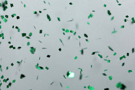 Shiny green confetti falling down on light gray backgroundの写真素材