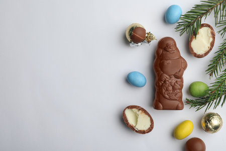 Flat lay composition with chocolate Santa Claus, fir tree twigs and sweets on white background, space for textの写真素材