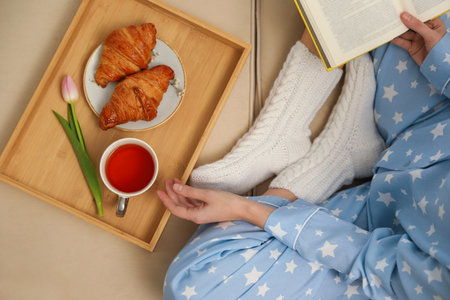 Woman with cup of tea and book resting on sofa, top viewの写真素材