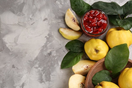 Delicious quince jam and fruits on light gray table, flat lay. Space for textの写真素材