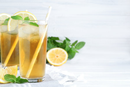 Delicious iced tea with lemon and mint on white wooden table. Space for textの写真素材